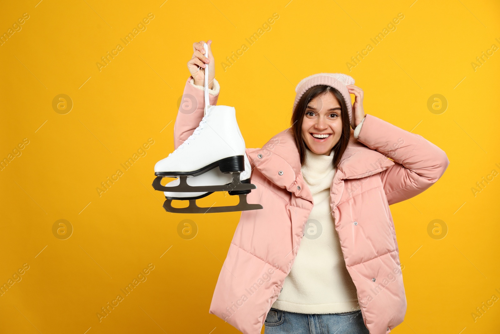 Photo of Emotional woman with ice skates on yellow background