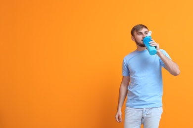 Photo of Young man with bottle of delicious milk shake on color background