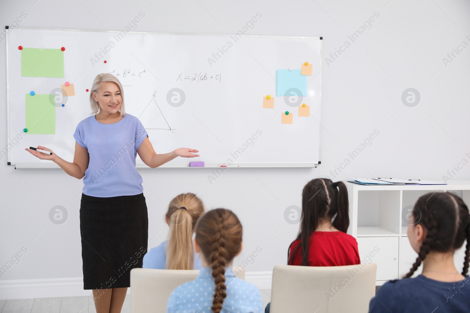 Photo of Mature teacher and students in modern classroom