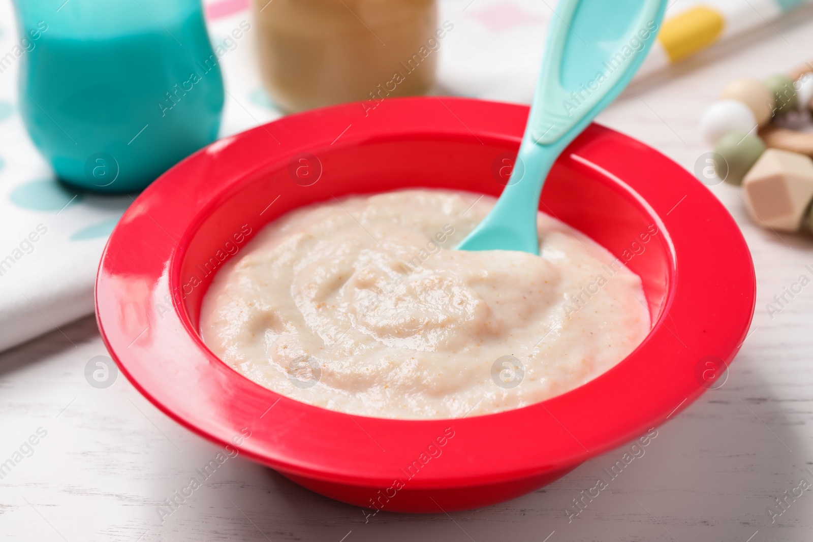 Photo of Healthy baby food in bowl on white wooden table, closeup