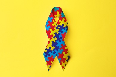 World Autism Awareness Day. Colorful puzzle ribbon on yellow background, top view