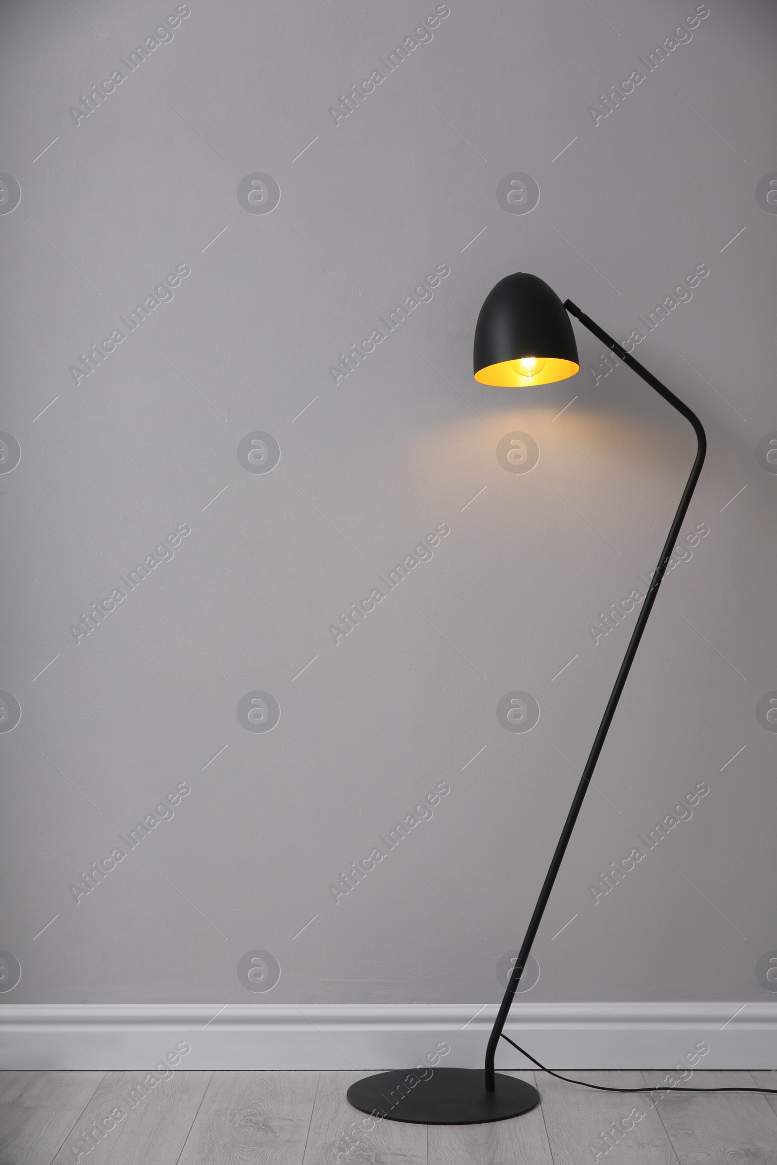 Photo of Modern floor lamp near light grey wall indoors, space for text. Interior element