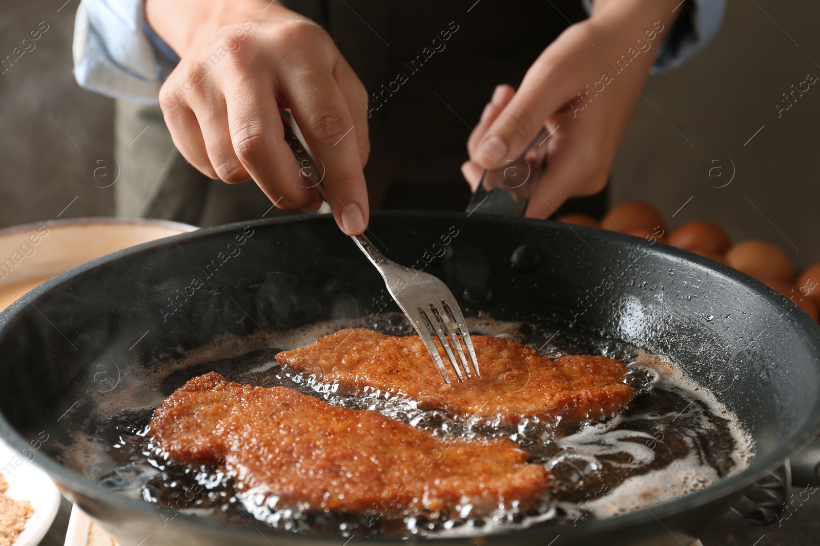 Photo of Woman cooking schnitzels in frying pan, closeup