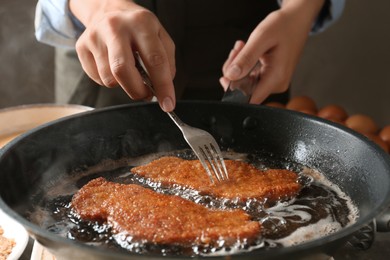 Photo of Woman cooking schnitzels in frying pan, closeup