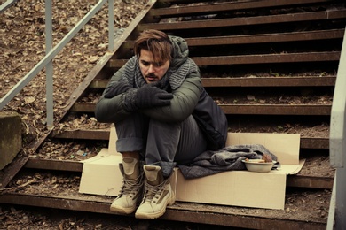 Photo of Poor young man sitting on stairs outdoors