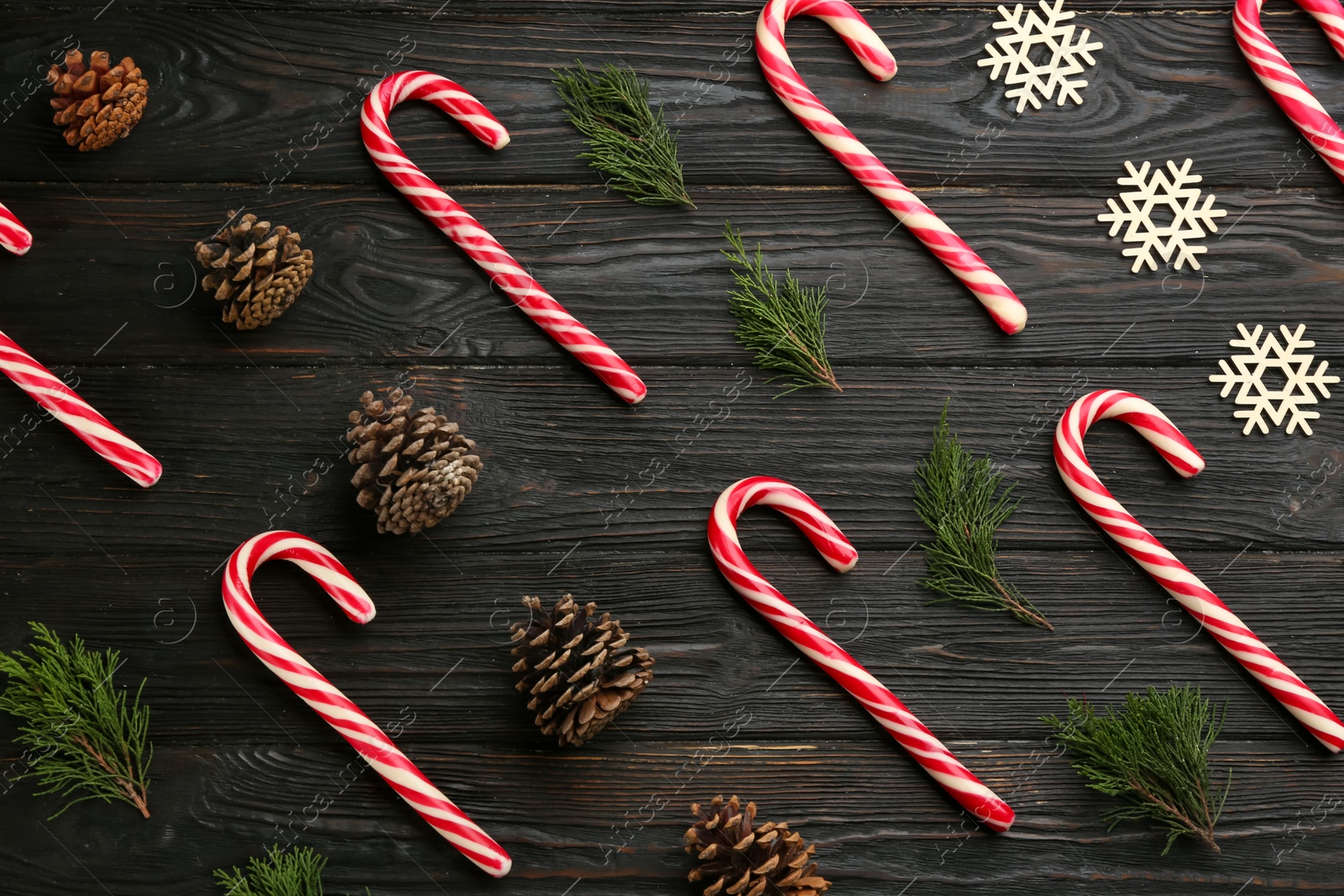 Photo of Flat lay composition with candy canes and Christmas decor on black wooden table