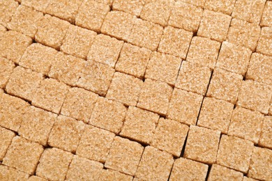 Brown sugar cubes as background, top view