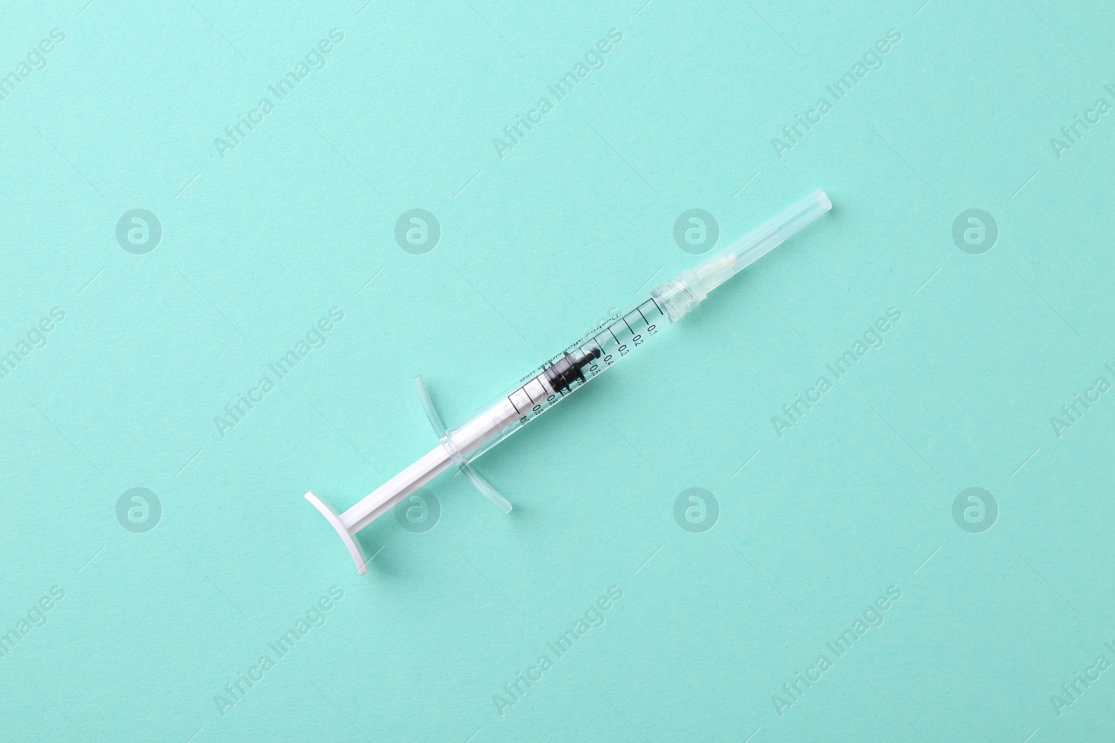 Photo of Injection cosmetology. One medical syringe on turquoise background, top view