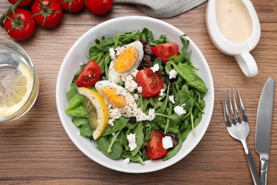 Photo of Delicious salad with boiled egg, tomatoes and cheese served on wooden table, flat lay