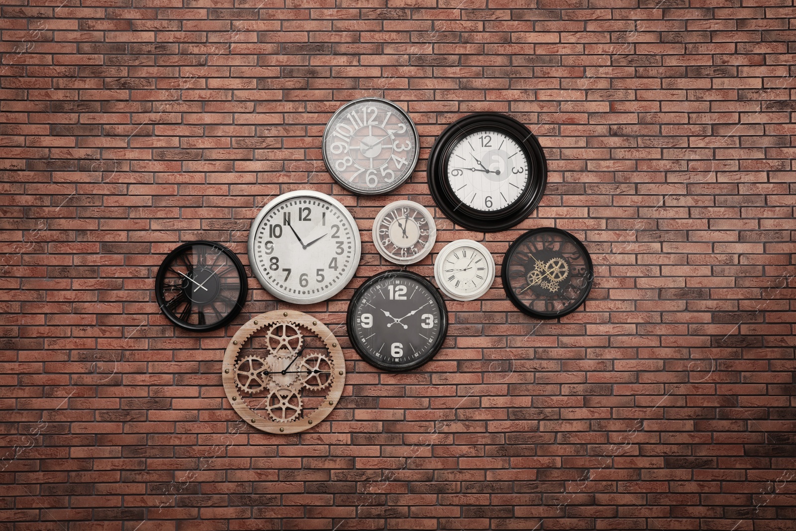 Photo of Collection of clocks hanging on red brick wall