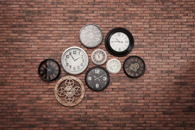 Collection of clocks hanging on red brick wall