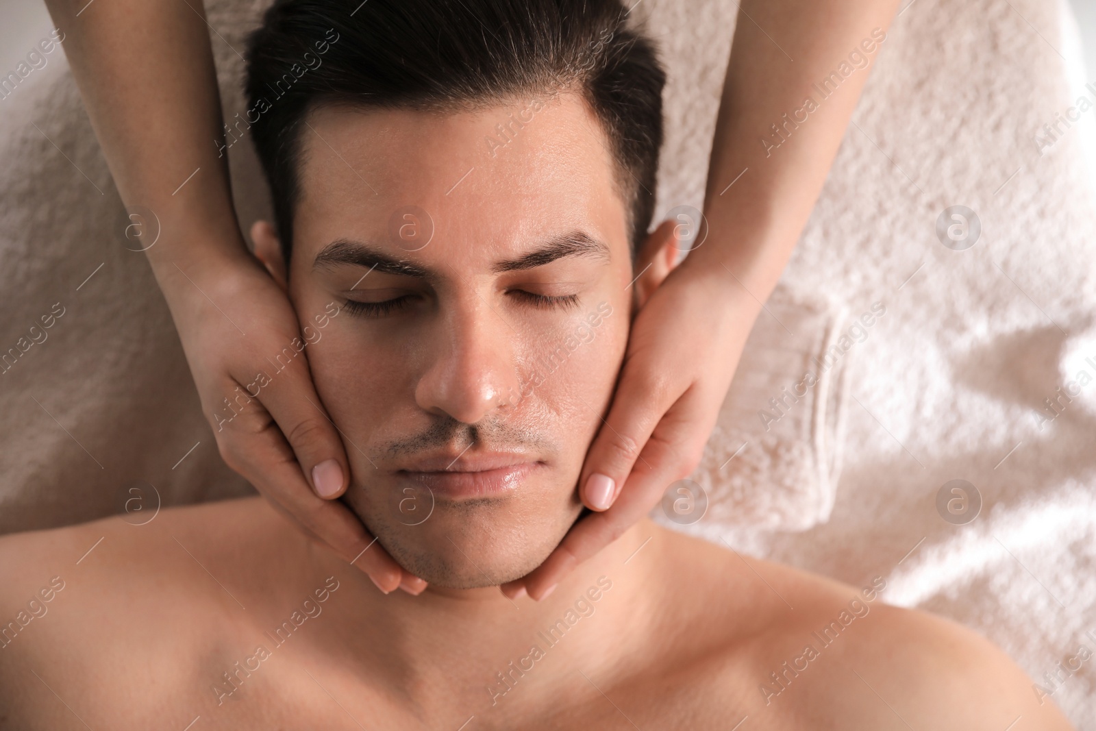 Photo of Man receiving facial massage in beauty salon, top view