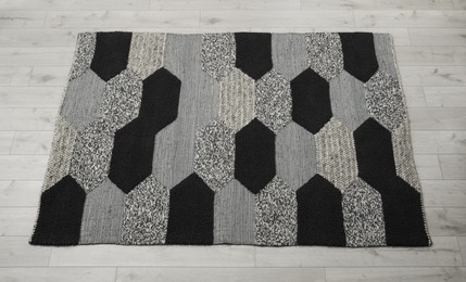 Carpet with geometric pattern on wooden floor, above view