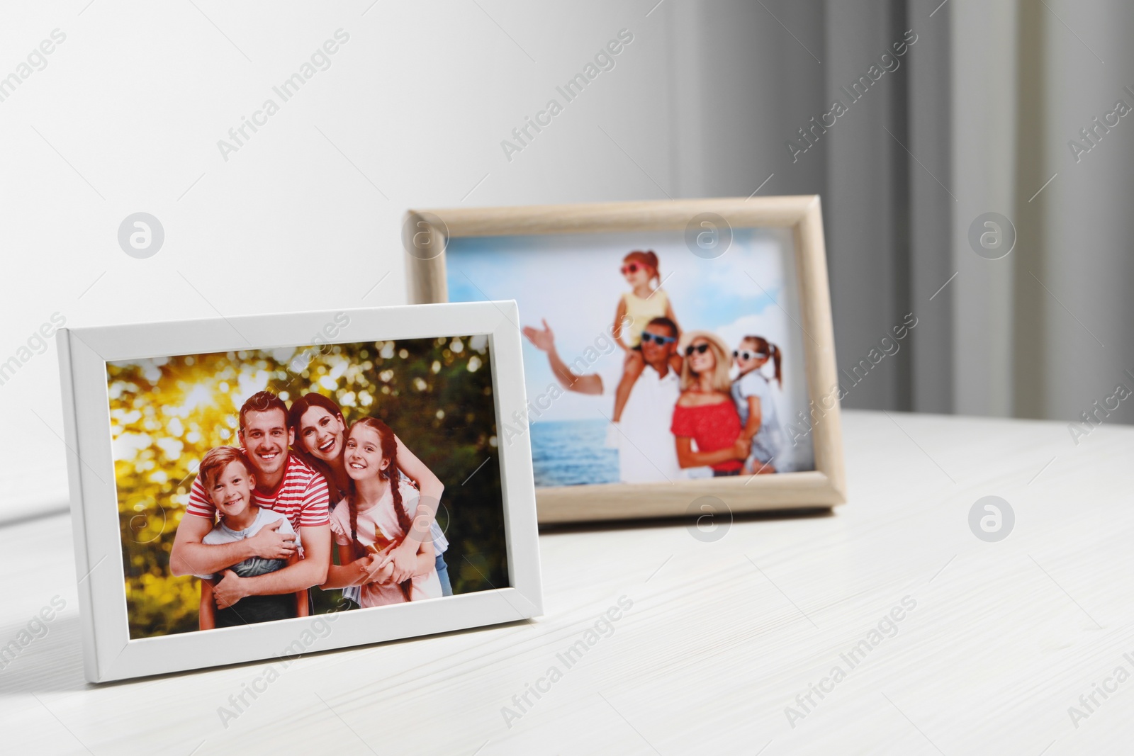 Photo of Framed family photos on white wooden table indoors. Space for text