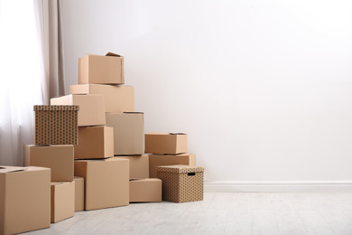 Photo of Pile of moving boxes in empty room, space for text