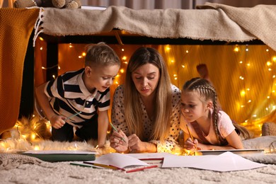 Mother and her children drawing in play tent at home