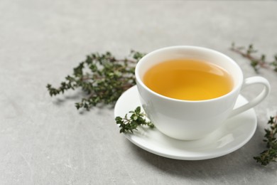 Photo of Aromatic herbal tea with thyme on light grey table. Space for text