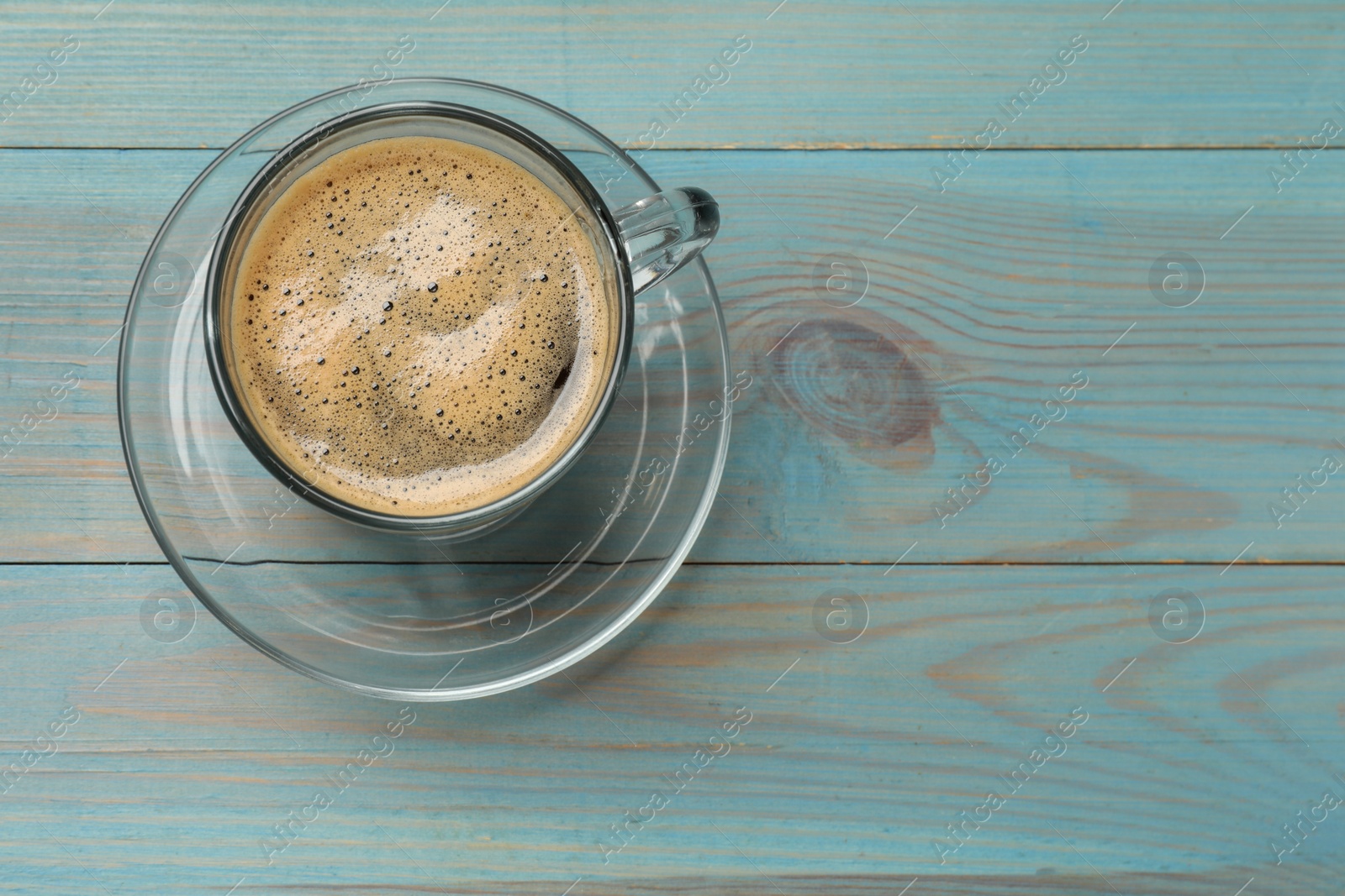 Photo of Cup of aromatic coffee on light blue wooden table, top view. Space for text