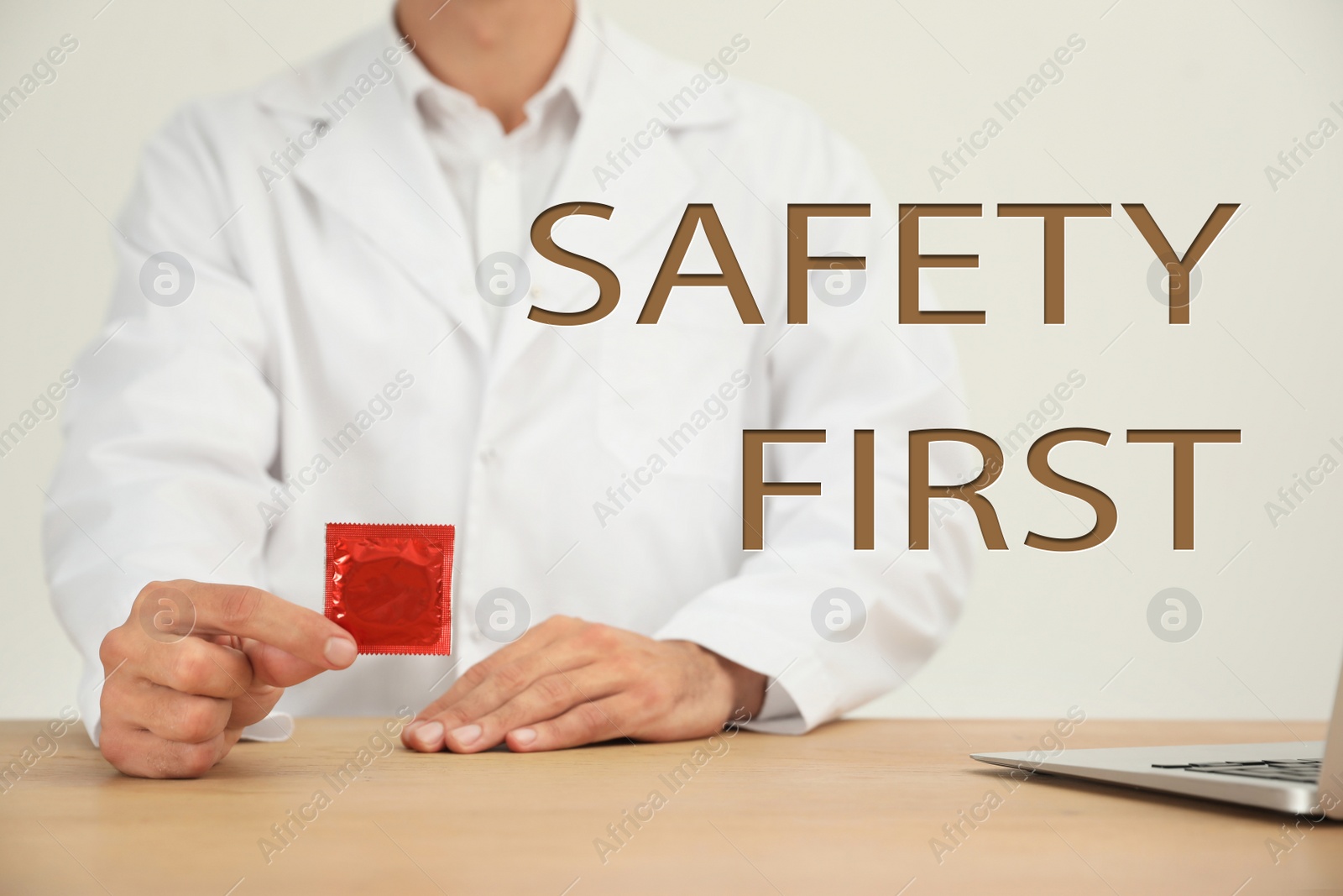 Image of Safety first. Doctor holding condom at wooden table, closeup