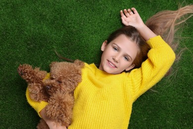 Photo of Little child with cute puppy on green grass, top view. Lovely pet