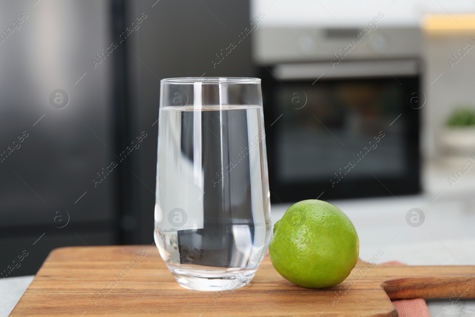 Photo of Filtered water in glass and lime on table in kitchen, closeup