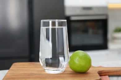 Photo of Filtered water in glass and lime on table in kitchen, closeup