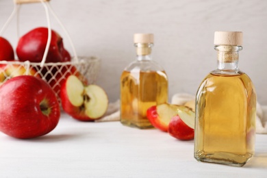 Photo of Composition with bottle of apple vinegar on table. Space for text