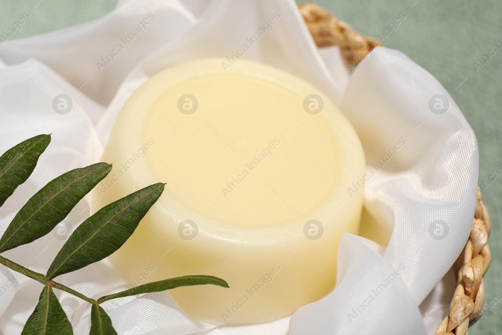 Photo of Solid shampoo bar in wicker basket, closeup view