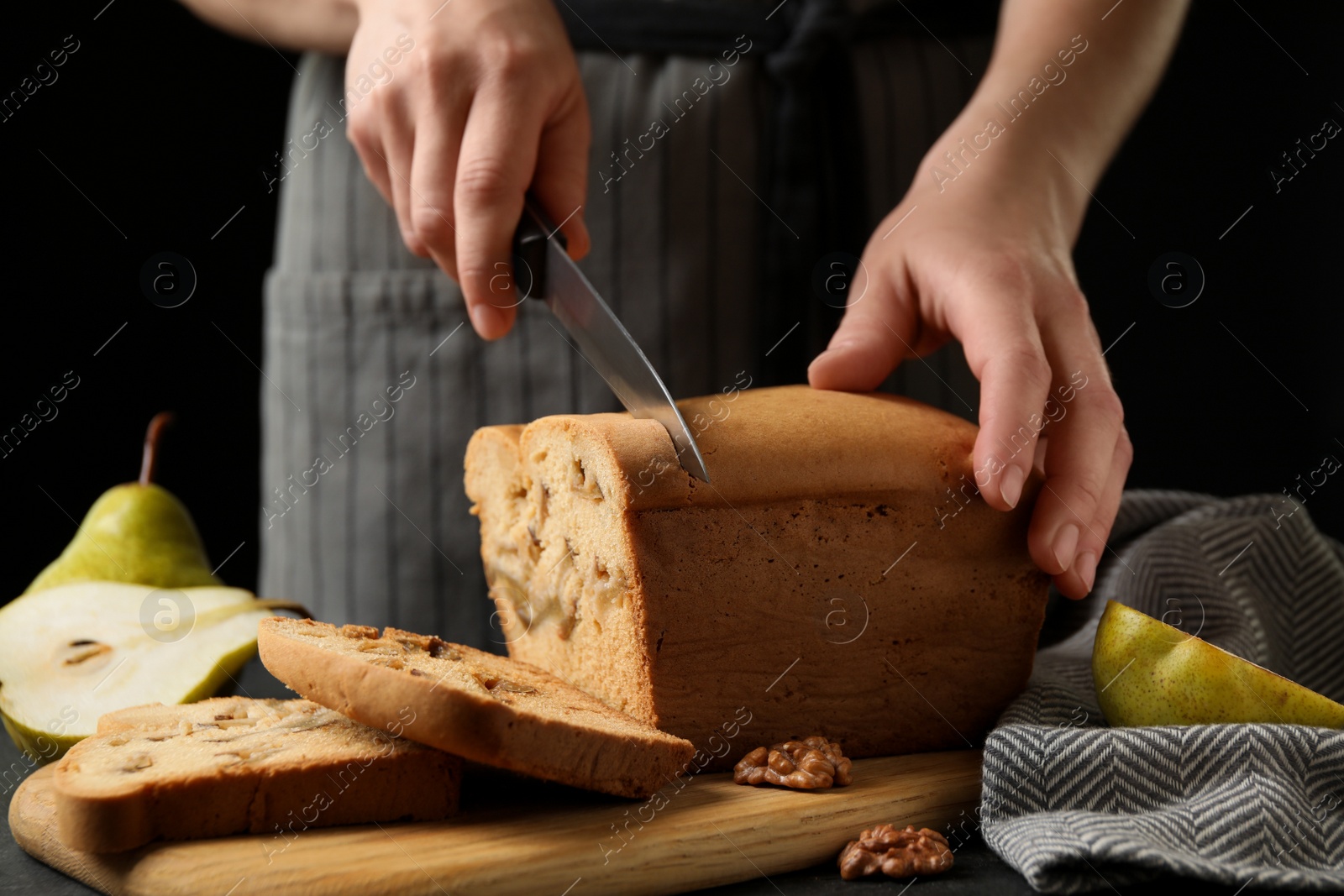 Photo of Woman cutting pear bread at table, closeup. Homemade cake