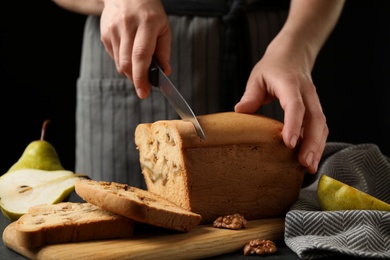 Photo of Woman cutting pear bread at table, closeup. Homemade cake