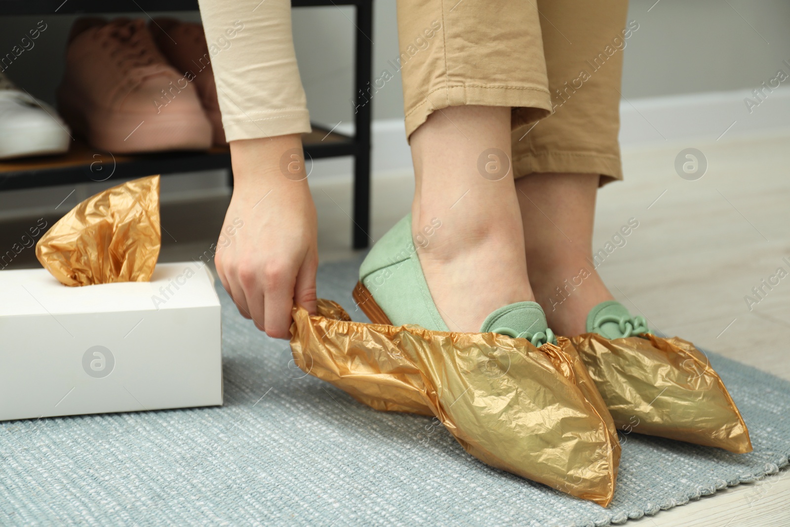 Photo of Woman wearing shoe covers onto her mules indoors, closeup