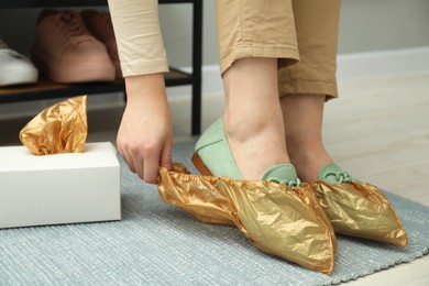 Woman wearing shoe covers onto her mules indoors, closeup