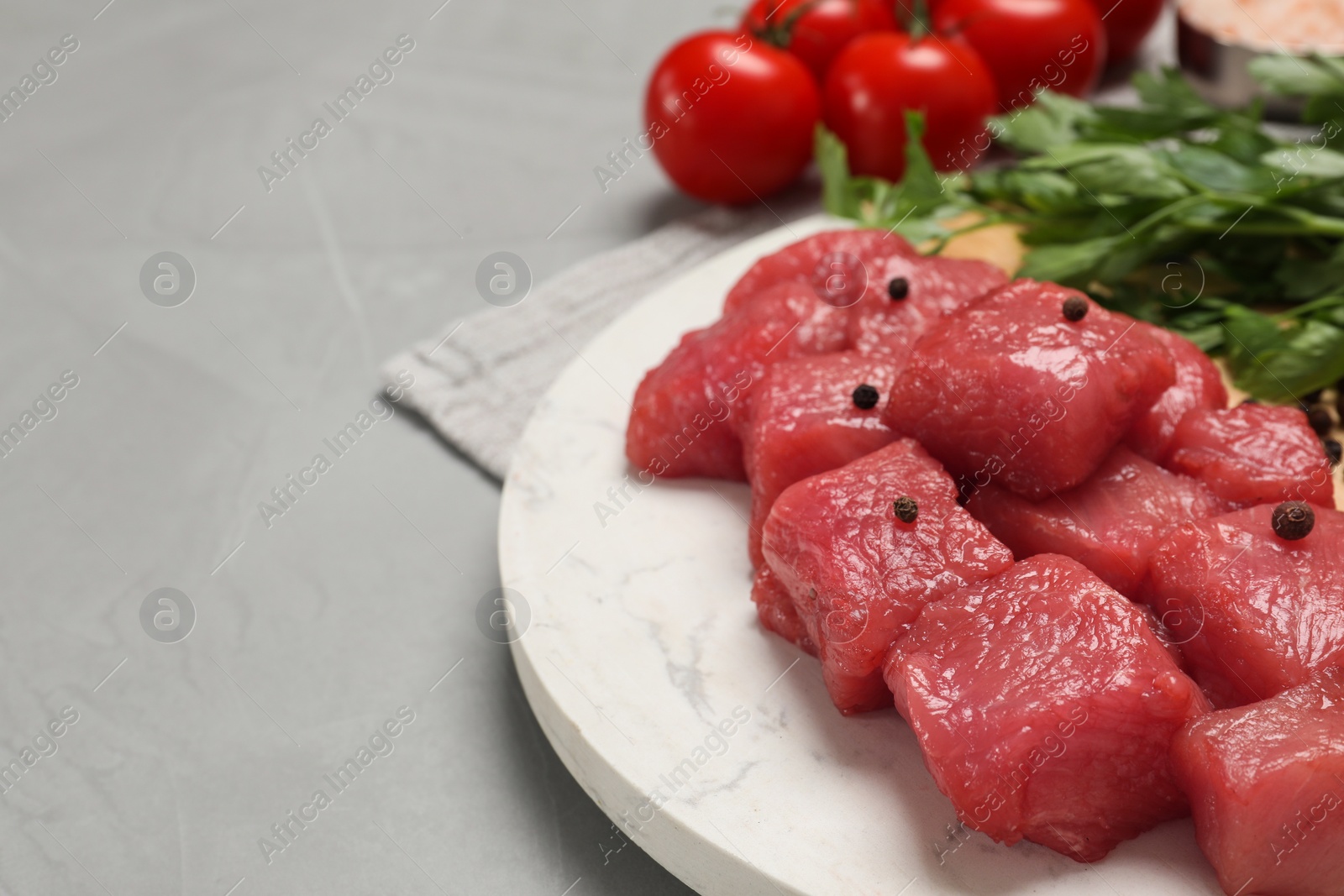 Photo of Cooking delicious goulash. Raw beef meat with spices on light grey table, space for text
