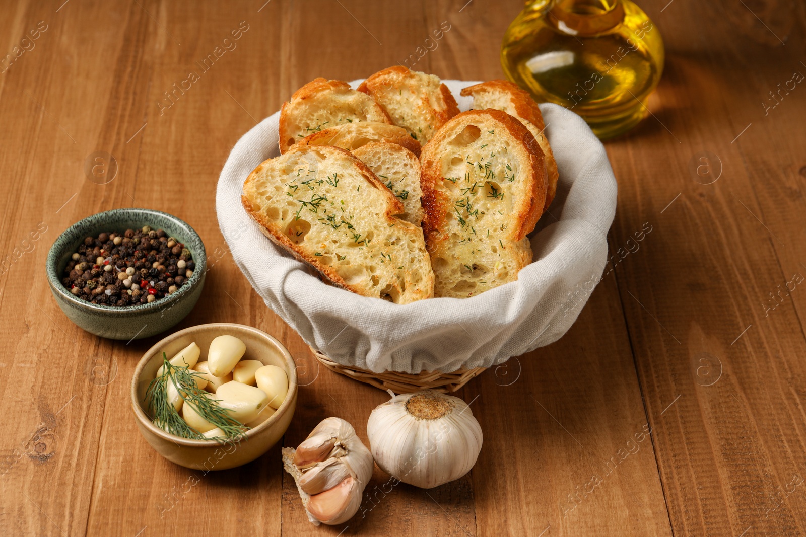Photo of Tasty baguette with garlic, oil and other spices on wooden table