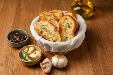 Tasty baguette with garlic, oil and other spices on wooden table