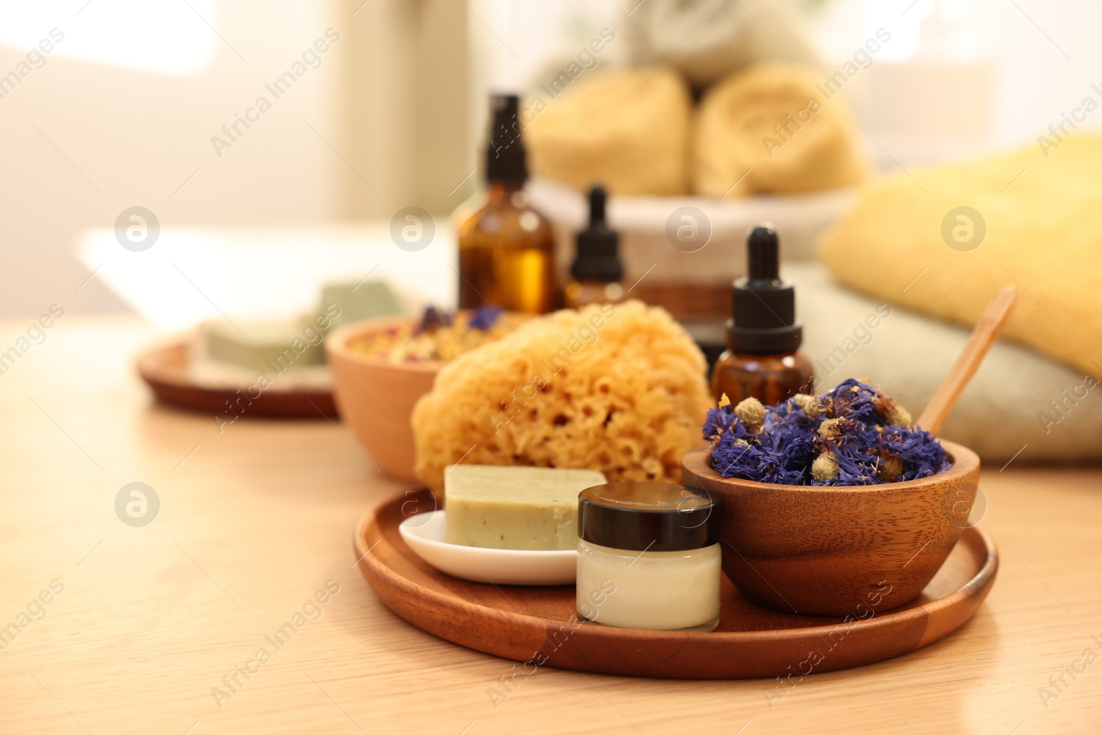 Photo of Dry flowers, loofah, soap bar, bottle of essential oil and jar with cream on wooden table indoors, space for text. Spa time