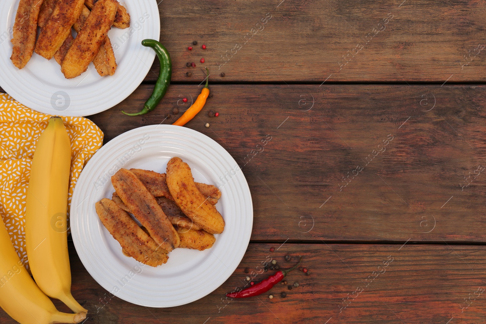 Photo of Delicious fried bananas, fresh fruits and different peppers on wooden table, flat lay. Space for text