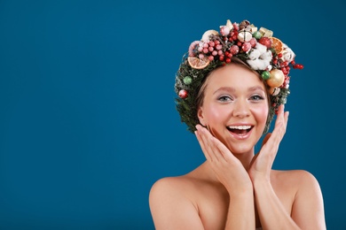 Photo of Pretty emotional young woman wearing Christmas wreath on blue background. Space for text