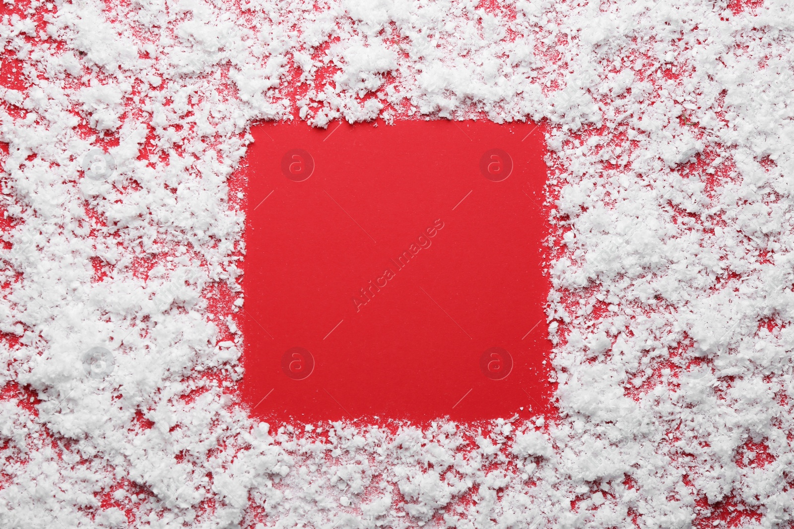 Photo of Frame made of snow on red background, top view with space for text. Winter season