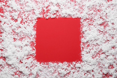 Frame made of snow on red background, top view with space for text. Winter season