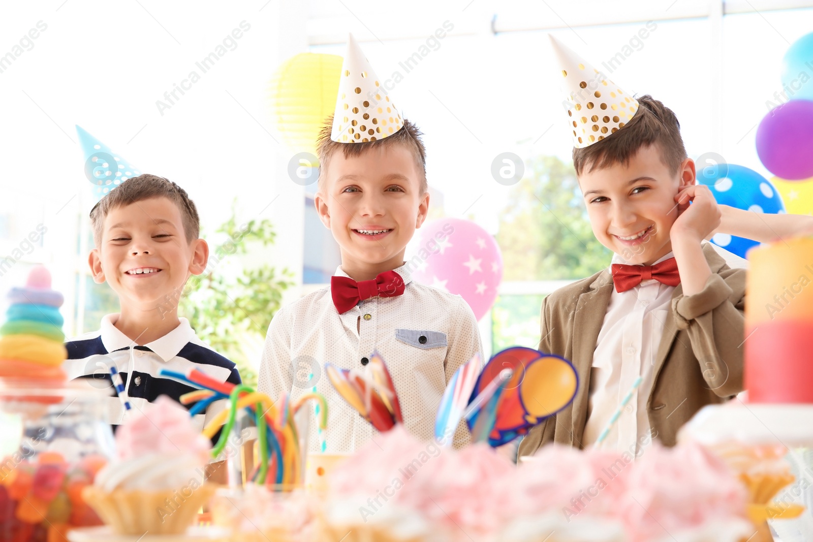 Photo of Cute children near table with treats at birthday party indoors