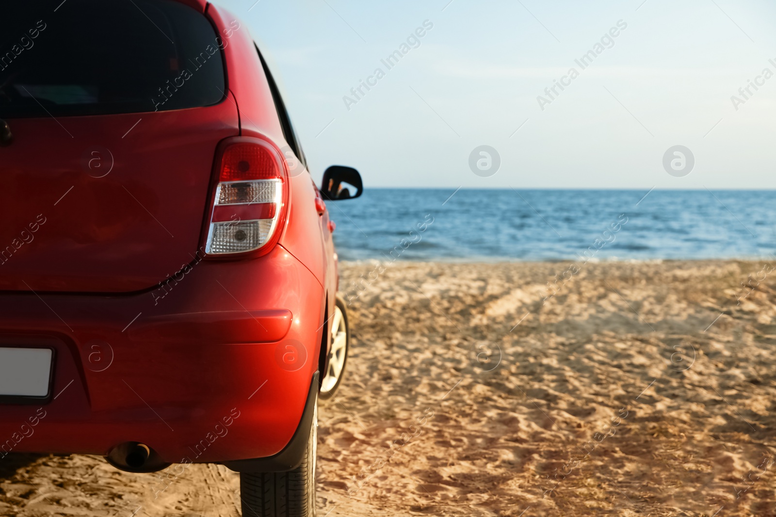 Photo of Modern red car on sandy beach, space for text. Summer trip