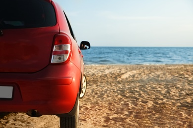 Photo of Modern red car on sandy beach, space for text. Summer trip