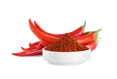 Photo of Fresh chili peppers and bowl of paprika powder on white background