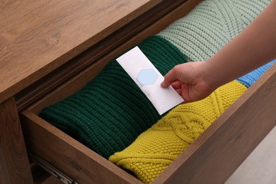 Photo of Woman putting scented sachet into drawer with clothes, closeup