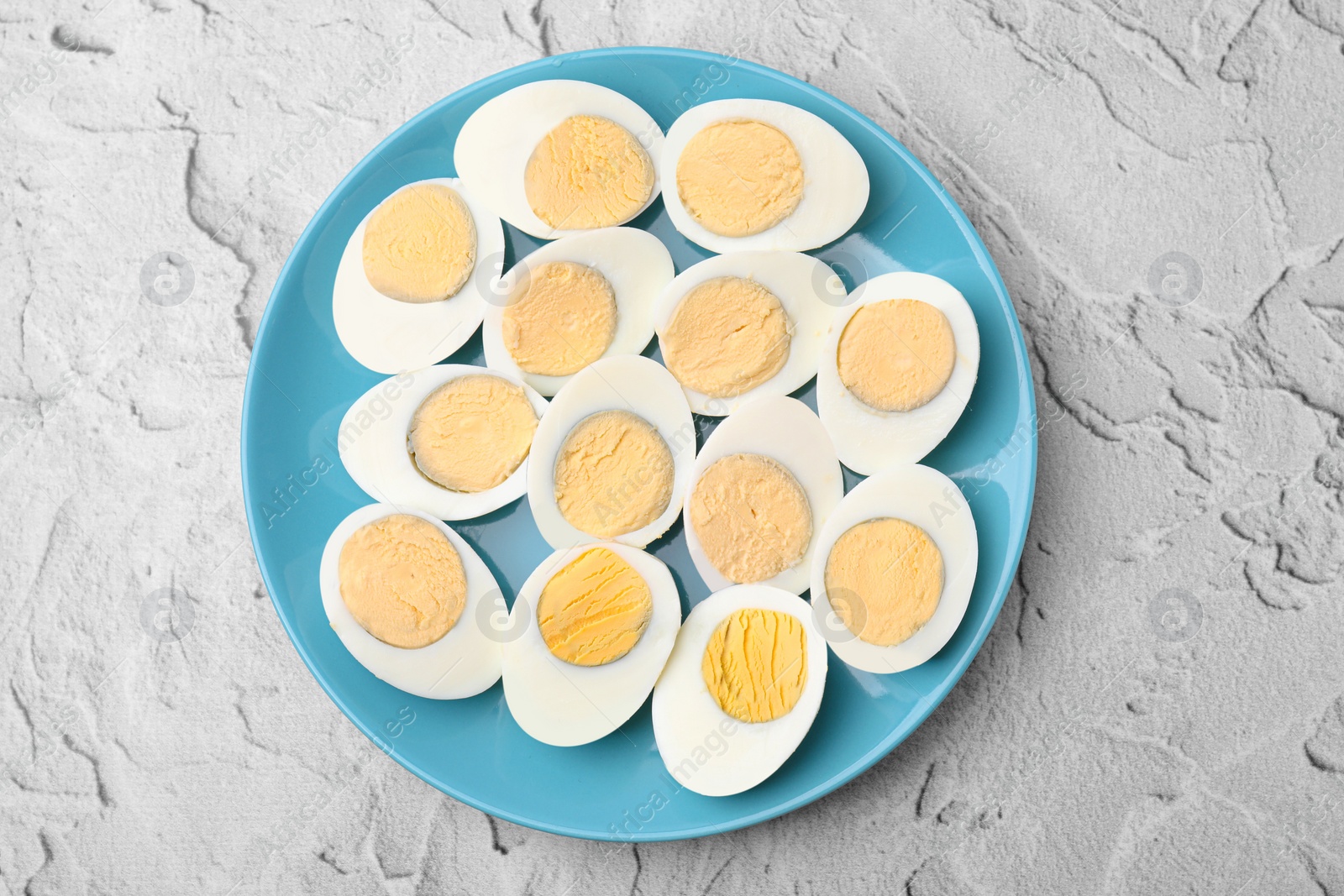 Photo of Fresh hard boiled eggs on light grey textured table, top view