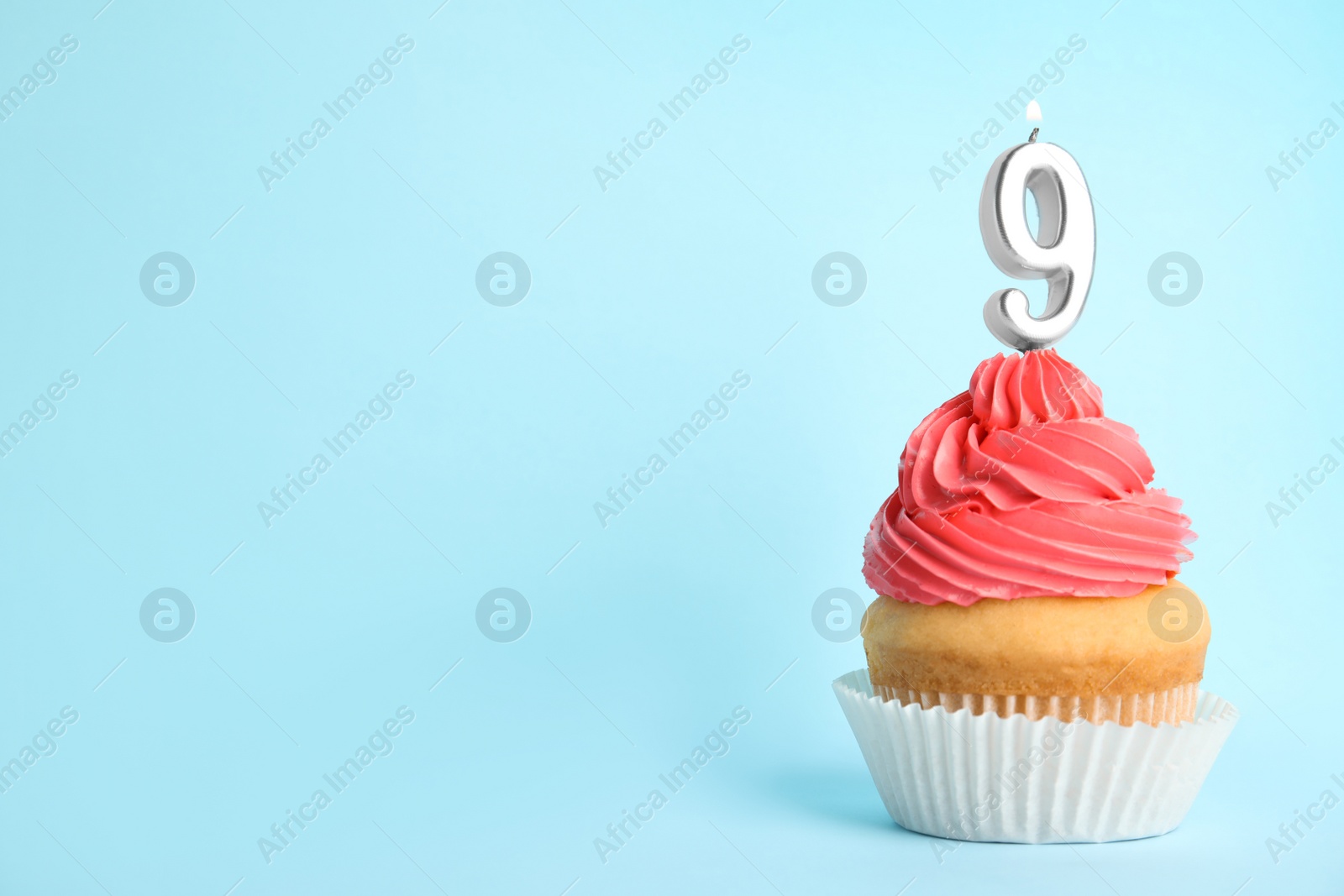 Photo of Birthday cupcake with number nine candle on blue background, space for text