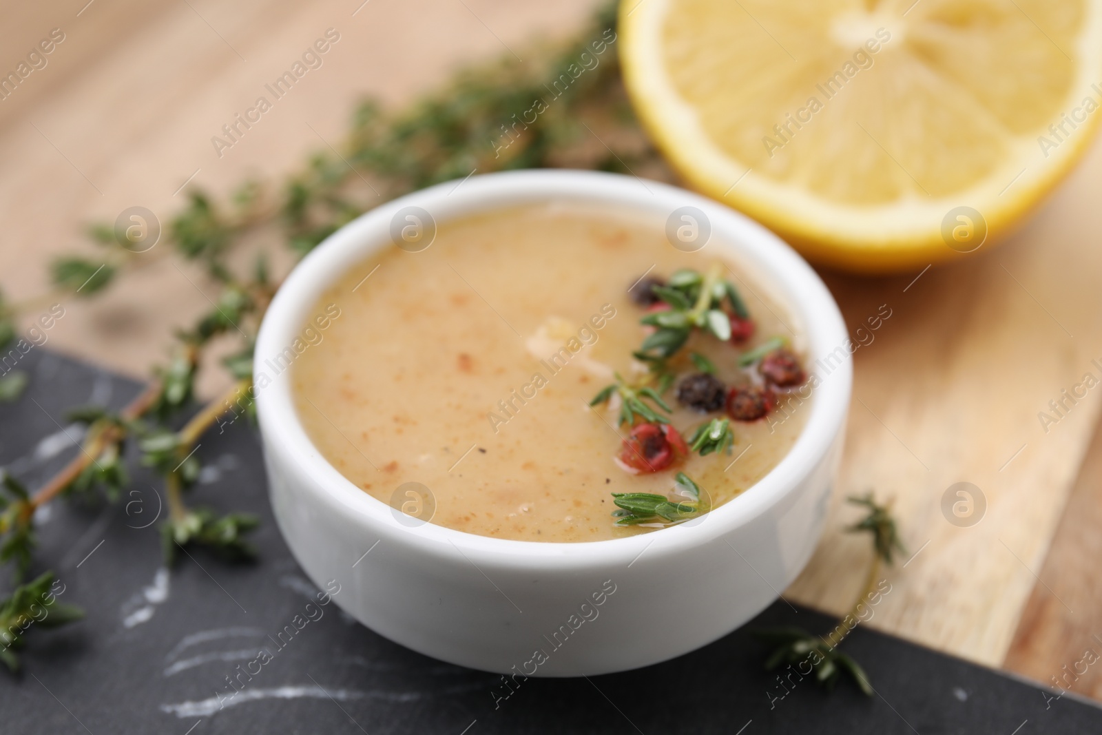 Photo of Delicious turkey gravy, thyme and peppercorns on table, closeup