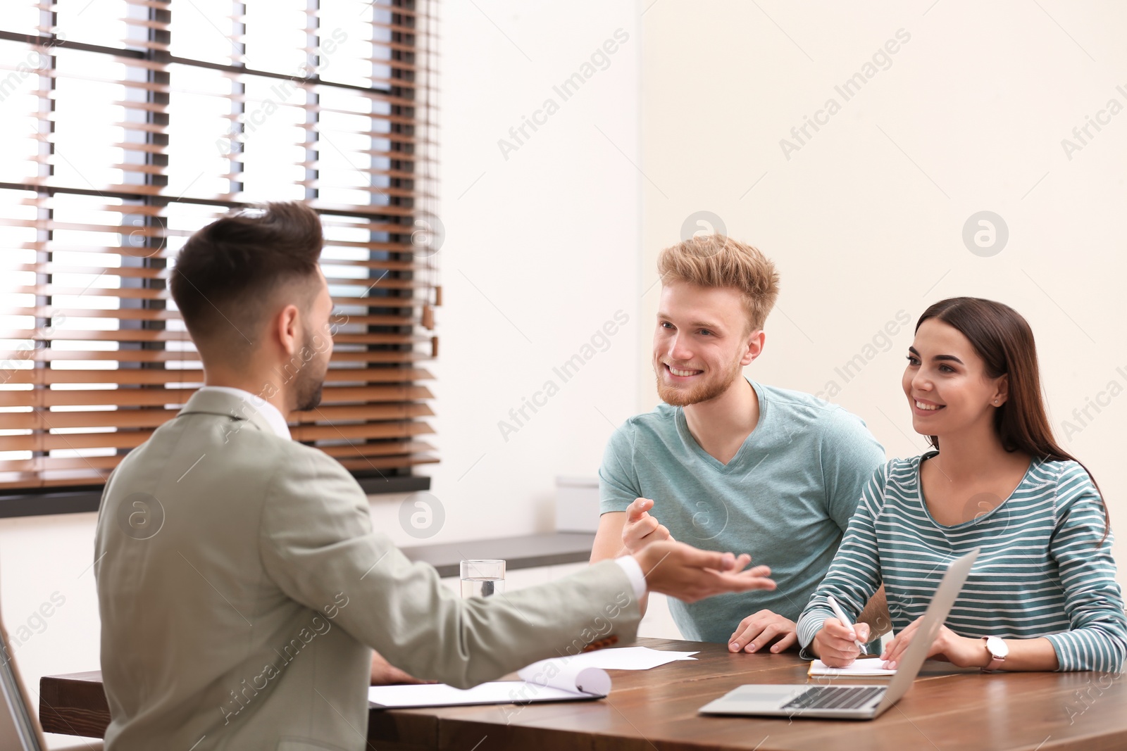 Photo of Insurance agent consulting young couple in office