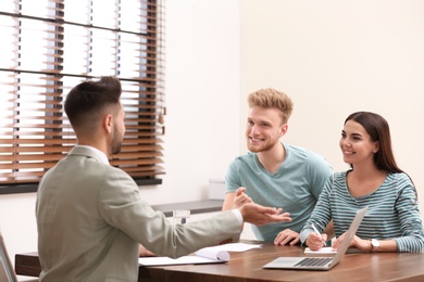 Photo of Insurance agent consulting young couple in office